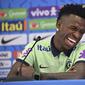 Penyerang Brasil #20 Vinicius Junior tertawa saat memberikan konferensi pers jelang Kroasia vs Brasil pada perempat final Piala Dunia 2022, di Stadion Al Arabi SC di Doha, Rabu (7/12/2022). Vinicius Jr dibuat kaget oleh seekor kucing ketika sedang menghadiri konferensi pers. (NELSON ALMEIDA / AFP)