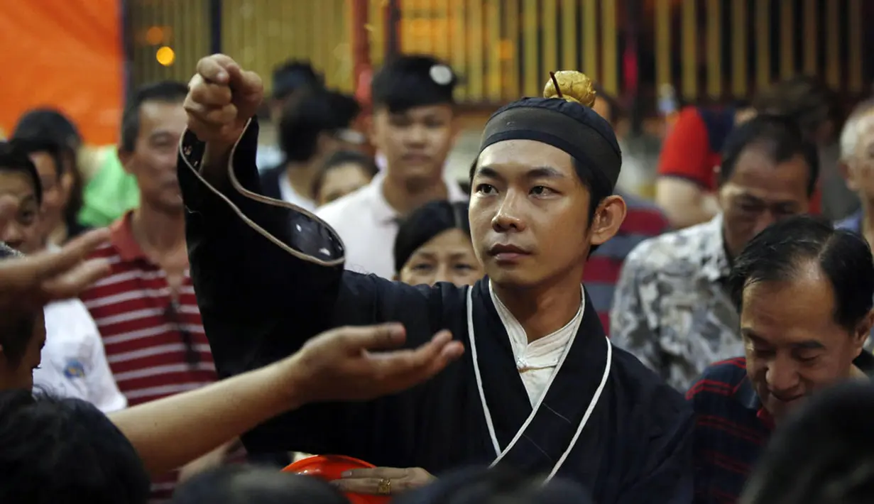 Seorang Biksu melempar koin keberuntungan ke arah warga selama festival Hungry Ghost, Kuala Lumpur, (3/8/2014). (REUTERS/Olivia Harris)