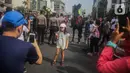 Seorang anak berfoto dengan latar polisi berkuda dari Direktorat Polisi Satwa Mabes Polri yang mengawasi keamanan di kawasan Bundaran HI, Jakarta, Minggu (17/11/2019). Polisi berkuda tersebut khusus ditugaskan mengawasi keamanan CFD serta memperkenalkan kepada warga. (Liputan6.com/Faizal Fanani)