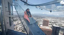 Seorang wanita mencoba berseluncur menggunakan skyslide di lantai 69 dan 70 dari Bank Tower AS, Los Angeles , California, (20/6). OUE Skyspace LA adalah tempat paling tinggi di California. (REUTERS / Lucy Nicholson)