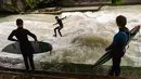 Peselancar meniti ombak saat bermain "surfing" di sungai buatan Eisbach yang terletak di English Garden Munich, Jerman pada 28 Mei 2019. Eisbach merupakan salah satu tempat berselancar sungai yang paling populer di kota Munich. (Photo by Peter Kneffel/dpa/AFP)