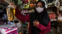 Seorang pedagang menimbang minyak goreng curah di kiosnya Pasar Kebayoran Lama, Jakarta, Rabu (19/1/2022). Pemerintah resmi mengimplementasikan kebijakan minyak goreng satu harga Rp14.000 per liter untuk semua jenis kemasan mulai hari ini. (Liputan6.com/Johan Tallo)