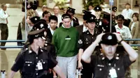 Nick Leeson tiba di bandara Changi Singapura dikelilingi oleh petugas polisi setempat pada 23 November 1995 setelah diusir oleh Jerman untuk diadili atas tuduhan penipuan dan pemalsuan atas runtuhnya Bank Barings Inggris pada Februari 1995. (AFP/JOHN MACDOUGALL)