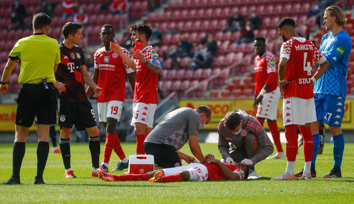 Gelandang FSV Mainz, Leandro Barreiro Martins (tengah) mendapat perawatan medis usai mengalami cedera saat melawan Bayern Munich dalam laga lanjutan Liga Jerman 2020/2021 pekan ke-31 di Opel Arena, Mainz, Sabtu (24/4/2021). FSV Mainz menang 2-1 atas Bayern Munich. (AFP/Kai Pfaffenbach/Pool)