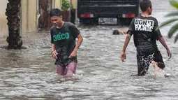 Warga melintasi banjir di jalan Pd. Karya, Jakarta, Kamis (13/12). Hujan yang mengguyur Jakarta Sore tadi menyebabkan banjir setinggi 40cm  menggenangi kawasan Jalan Pd. Karya dan Jalan Bangka. (Liputan6.com/Faizal Fanani)