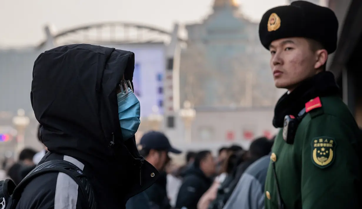 Seorang pria mengenakan masker penutup mulut setibanya di stasiun kereta api Beijing untuk mudik Tahun Baru Imlek pada Selasa (21/1/2020). Virus mirip SARS yang menyebar ke seluruh wilayah China dan mencapai tiga negara Asia ternyata dapat menular dari satu orang ke orang lain. (NICOLAS ASFOURI/AFP)
