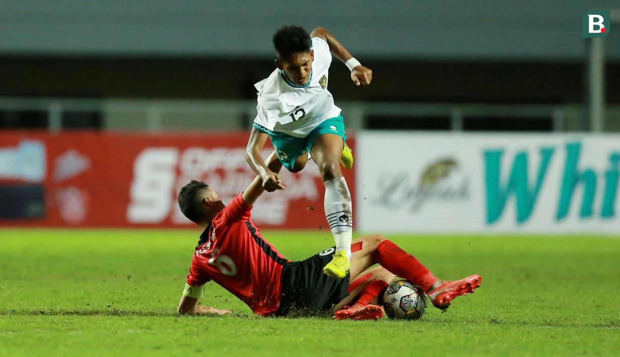 Pemain Timnas Indonesia U-17, Muhammad Narendra Tegar (atas) berusaha melewati hadangan pemain Palestina, Mohammed Manassra pada laga Grup B Kualifikasi Piala Asia U-17 2023 antara Timnas Indonesia menghadapi Palestina di Stadion Pakansari, Bogor, Jumat (7/10/2022). (Bola.com/M Iqbal Ichsan)