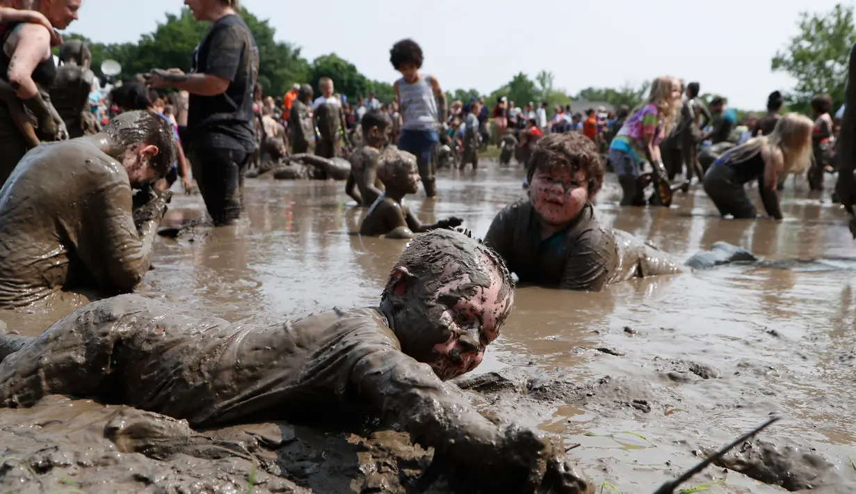 Christian Kubanek, 4, bermain dalam kubangan lumpur saat Mud Day atau Hari Lumpur di Michigan, negara bagian AS, Selasa (9/7/2019). Para peserta perayaan yang menjadi tradisi setiap tahun ini merupakan anak-anak untuk agar mereka bersenang-senang selama liburan musim panas.  (AP/Carlos Osorio)