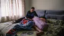 Ibu tunggal Tilda Kalaivani duduk di samping kedua anaknya yang tidur di apartemen sewaannya di Kuala Lumpur pada 6 Juli 2021. Warga Malaysia yang berjuang memenuhi kebutuhan sehari-hari selama pandemi corona yang memburuk, telah mengibarkan bendera putih untuk memohon bantuan. (Mohd RASFAN/AFP)