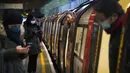 Para penumpang naik kereta Bawah Tanah Jubilee Line di Stasiun Canning Town selama jam sibuk di London, Inggris, 12 Januari 2021. Inggris sedang menerapkan lockdown nasional ketiga untuk mengekang penyebaran virus corona COVID-19. (Victoria Jones/PA via AP)