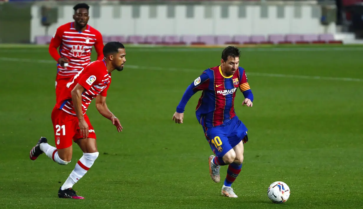 Pemain Barcelona Lionel Messi (kanan) menggiring bola melewati pemain Granada Yangel Herrera pada pertandingan La Liga di Stadion Camp Nou, Barcelona, Spanyol, Kamis (29/4/2021). Barcelona kalah 1-2. (AP Photo/Joan Monfort)