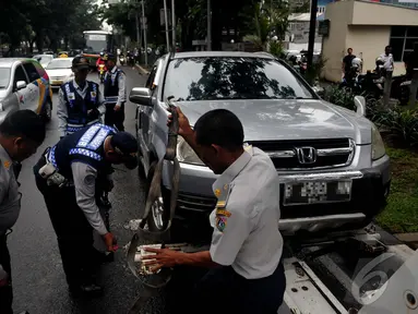 Petugas Dishub saat mengangkut mobil yang parkir sembarangan, Jakarta, Senin (12/1/2015). (Liputan6.com/Johan Tallo)