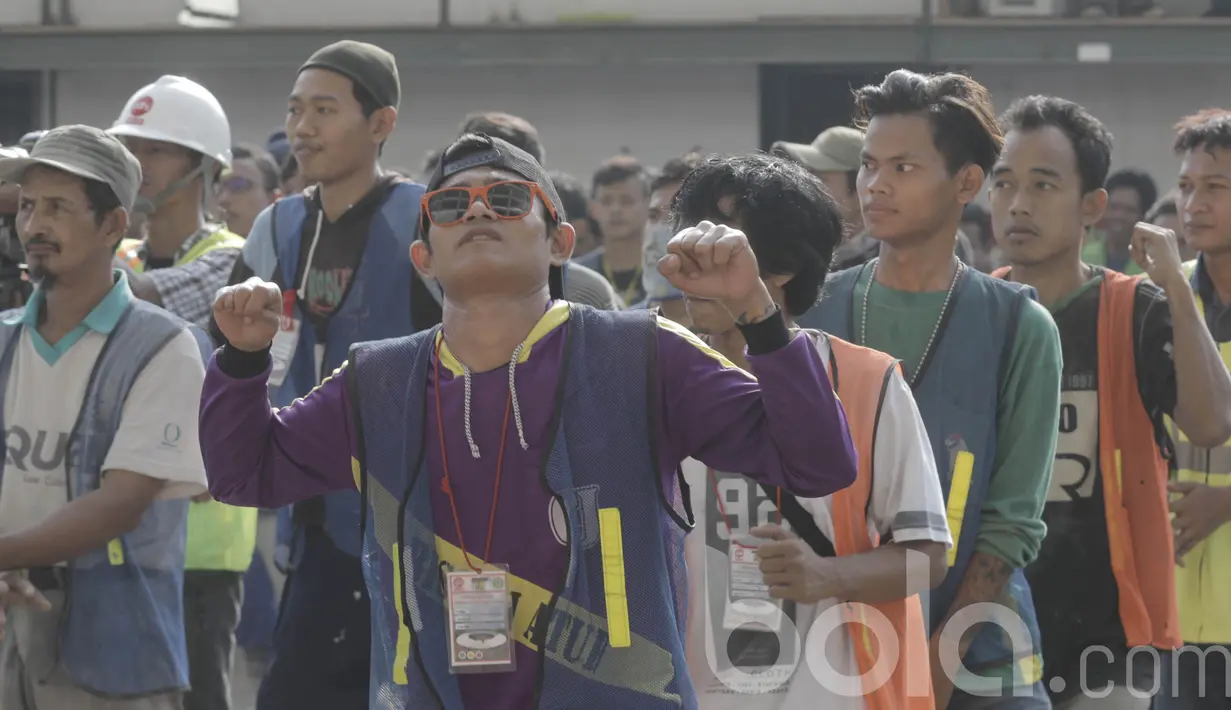Seorang pekerja menikmati senam sebelum bekerja di proyek renovasi Stadion Utama Gelora Bung Karno (SUGBK), Senayan. Senam tersebut untuk meningkatkan kebugaran dan semangat pekerja. (Bola.com/M Iqbal Ichsan)