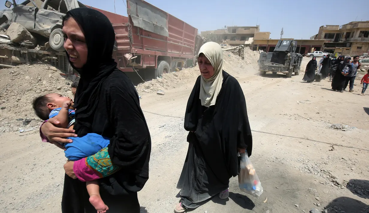 Warga sipil Irak menggendong anaknya saat mengungsi dari Kota Tua di Mosul, 1 Juli 2017. Dana Anak PBB (UNICEF) pada 29 Juni 2017, mengatakan ribuan anak telah terjebak di daerah yang masih dikuasai ISIS di pusat kota tua itu. (AHMAD AL-RUBAYE/AFP)