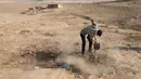 Warga Irak mengubur jenazah militan ISIS di Karamah, selatan Mosul, Irak (11/11). Pasukan khusus Irak dan warga Mosul menyeret jenazah pejuang ISIS sebelum akhirnya dikubur ke dalam liang lahat. (REUTERS/Goran Tomasevic)