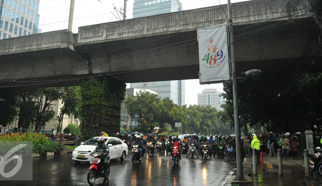 Pengendara sepeda motor berteduh di bawah flyover saat hujan turun, Jakarta, Rabu (13/7). Petugas kepolisian akan menerapkan tilang dengan denda maksimal Rp250.000 untuk pengendara yang berteduh di bawah flyover. (Liputan6.com/Gempur M Surya) 