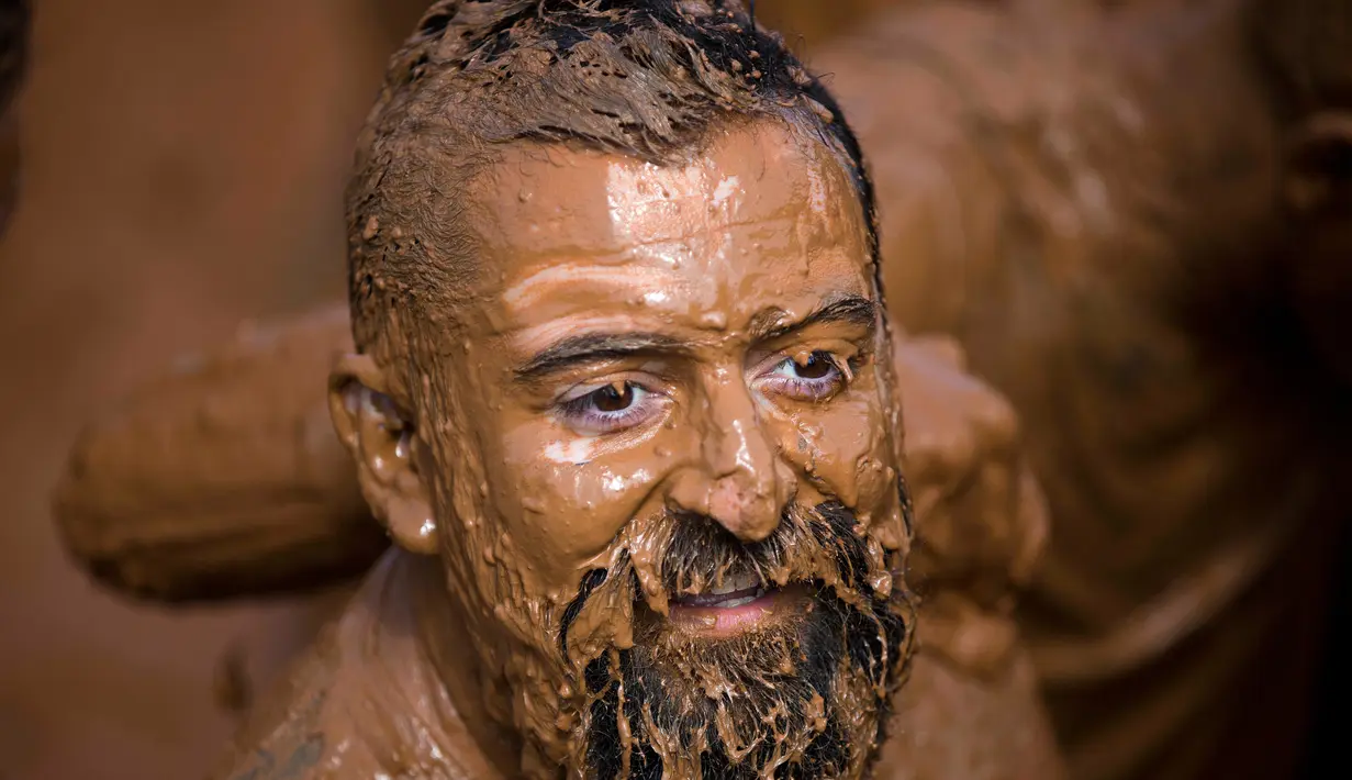 Ekpresi seorang pria saat mengikuti Mud Day di Tel Aviv, Israel (24/3). Para peserta harus menyelesaikan lomba lari sepanjang 13 kilometer yang dipenuhi rintangan dan kubangan. (AP Photo/Oded Balilty)