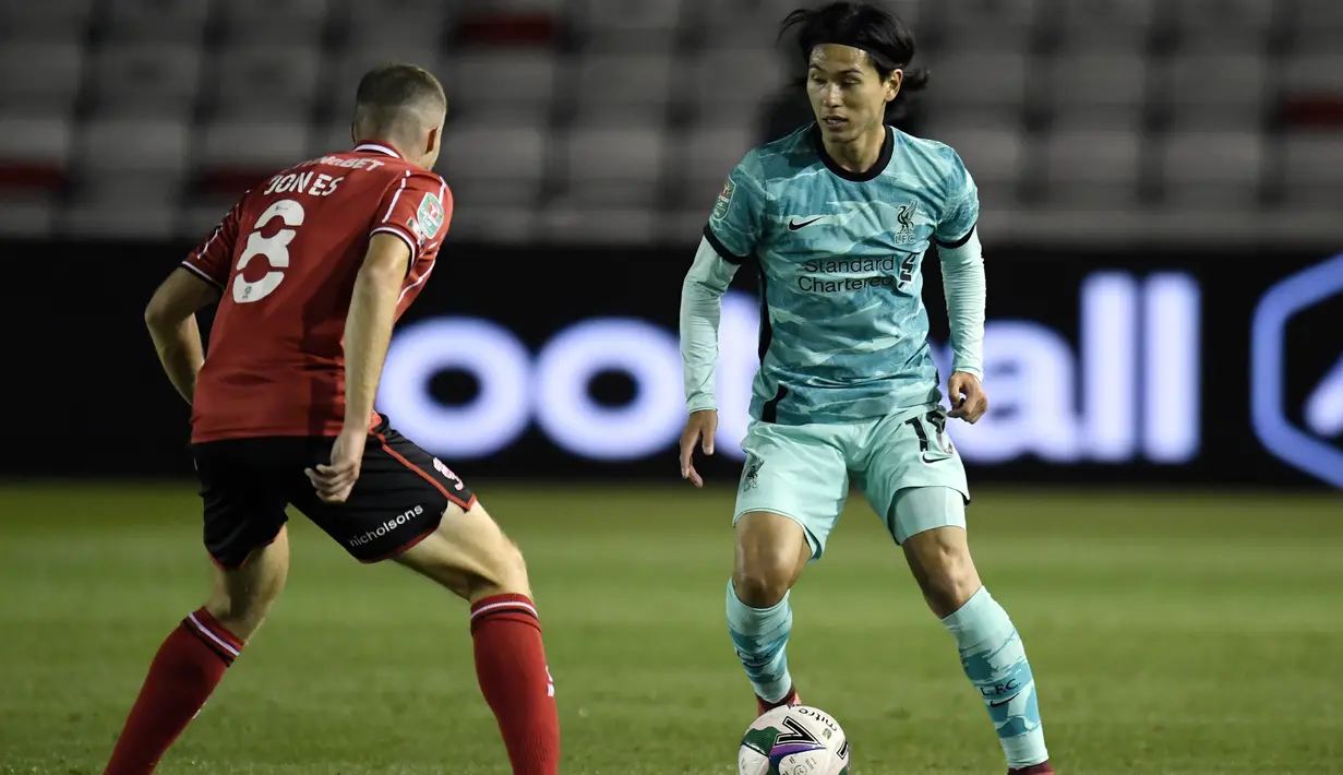 Gelandang Liverpool, Takumi Minamino, berebut bola dengan gelandang Lincoln City, James Jones, pada laga babak ketiga Piala Liga Inggris di Sincil Bank Stadium, Jumat (25/9/2020). Liverpool menang telak 7-2 atas Lincoln. (AFP/Peter Powell/pool)