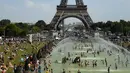 Turis dan warga menyejukkan diri dan berjemur di kolam Trocadero Fountains (air mancur Trocadero) dekat Menara Eiffel di Paris, Kamis (25/7/2019). Gelombang panas di Eropa mencapai puncaknya, bahkan suhu di ibu kota Prancis mencapai di atas 41 derajat Celcius. (Bertrand GUAY / AFP)