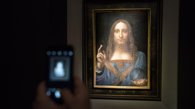 Seorang pengunjung mengambil foto lukisan 'Salvator Mundi' karya Leonardo da Vinci di Christie's New York Auction House, New York City (15/11). Lukisan wajah Yesus Kristus karya da Vinci ini terjual seharga US$ 450,3 juta. (Drew Angerer/Getty Images/AFP)