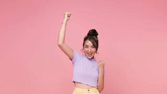 Seorang perempuan sedang tersenyum sambil mengangkat tinggi tangan kanannya (Foto Dok: Freepik/ our-team)