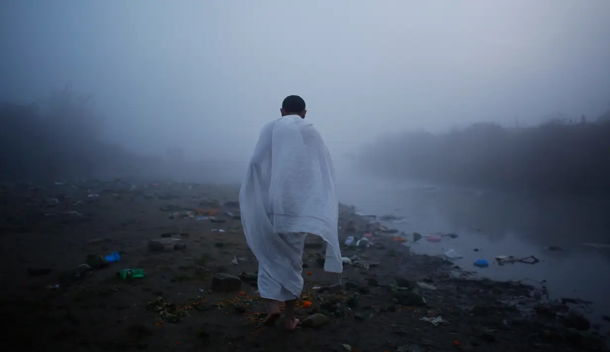 Seorang pria berjalan menuju sungai Bagmati untuk melakukan ritual selama Festival Gaya Aunsi di Kathmandu, Nepal (21/12). Ritual suci ini digelar untuk memberi doa dan penghormatan kepada anggota keluarga yang telah meninggal.(AP Photo/Niranjan Shrestha)