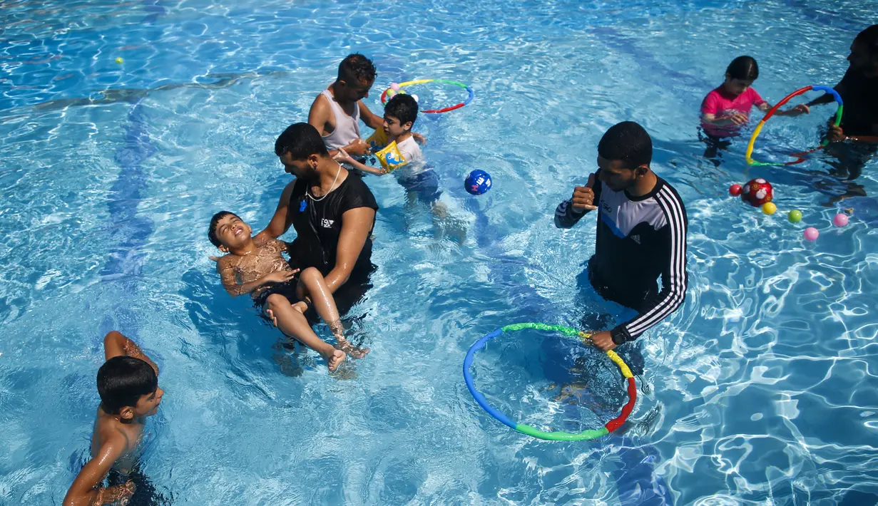 Anak-anak Palestina yang menderita autisme berpartisipasi dalam sesi terapi renang di Beit Lahia di Jalur Gaza utara  (5/8/2019). (AFP Photo/Mohammed Abed)
