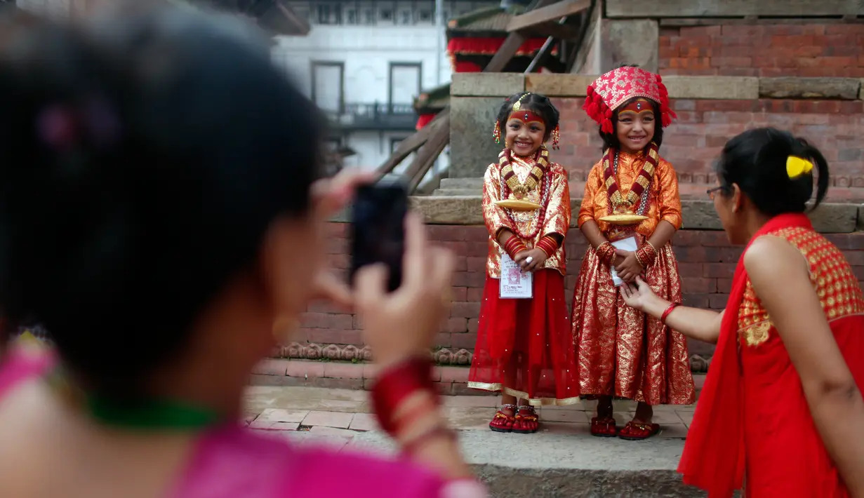 Dua anak perempuan Nepal tersenyum saat foto bersama saat acara tradisi Kumari di Hanuman Dhoka, Kathmandu, Nepal, Senin (4/9). Anak perempuan di bawah usia 9 tahun dianggap sebagai wujud nyata dari Dewi yang “hidup”. (AP Photo/Niranjan Shrestha)