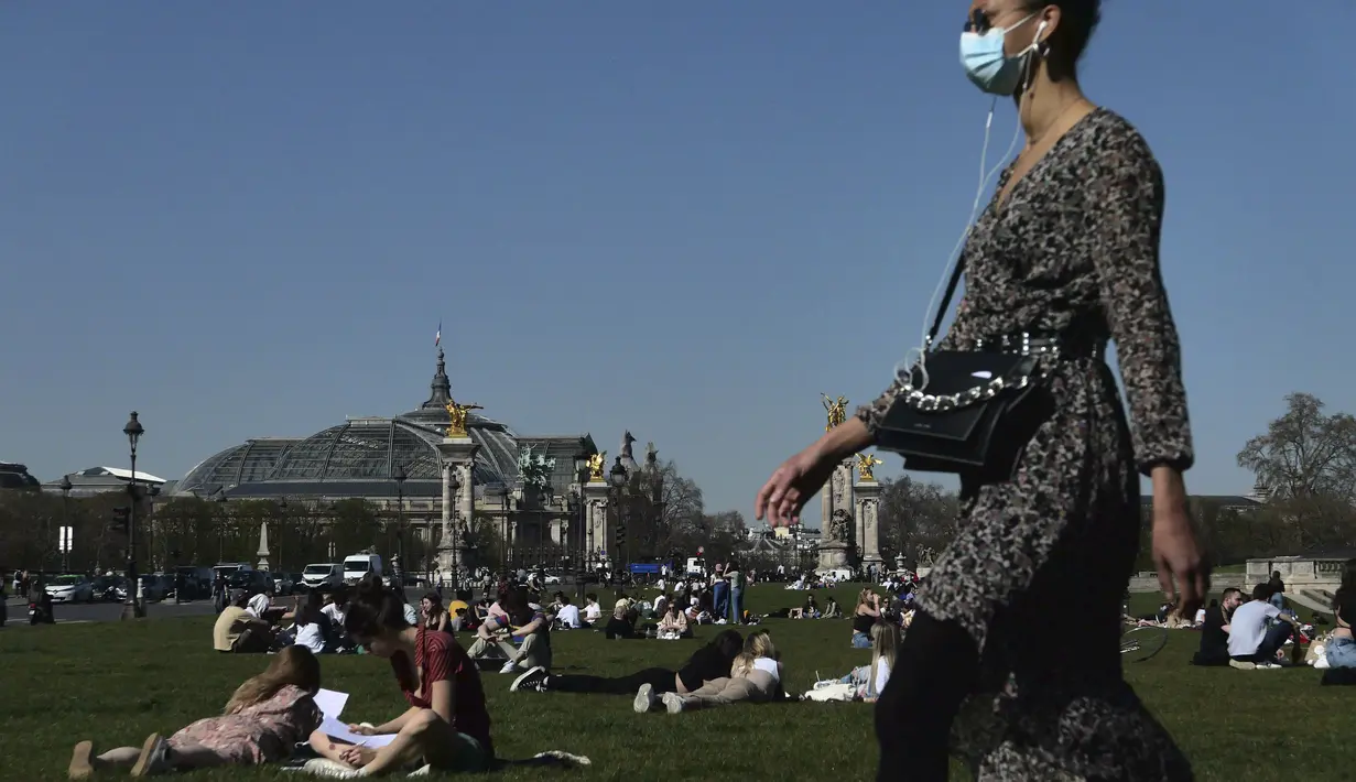 Orang-orang bersantai saat menikmati matahari di Esplanades des Invalides di Paris, Selasa (30/3/2021). Cuaca panas diperkirakan akan berlangsung selama beberapa hari di seluruh negeri. (AP Photo/Christophe Ena)