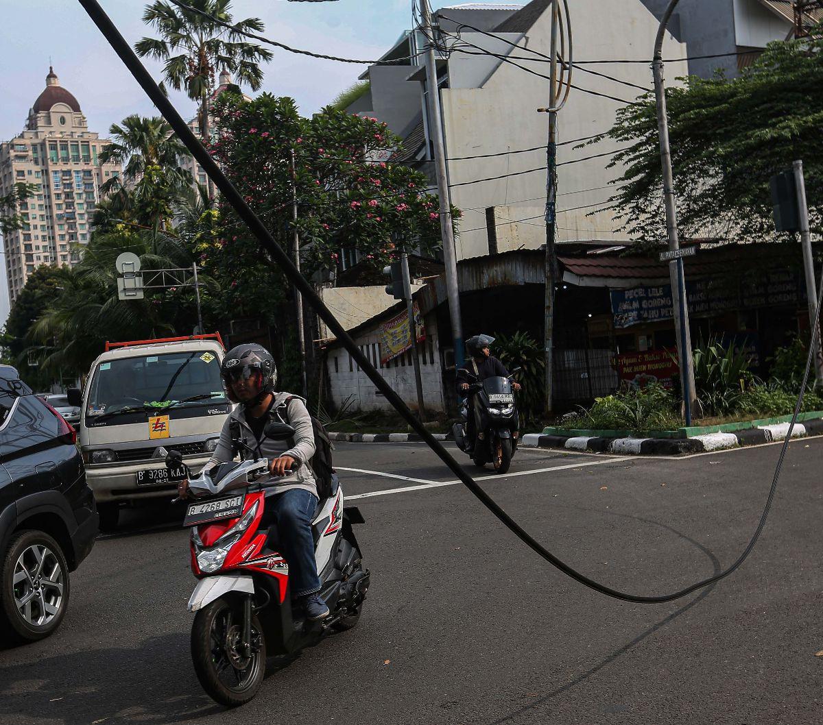 Sejumlah kendaraan melintas di dekat kabel menjuntai di Jalan Patal Senayan, Jakarta Selatan, Selasa (2/7/2024). Kabel tersebut menjuntai hingga nyaris menyentuh aspal setelah tersangkut pada sebuah truk bermuatan melebihi tinggi maksimum.&nbsp;Liputan6.c