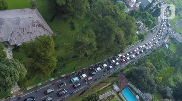 Foto udara memperlihatkan kendaraan wisatawan di Jalan Raya Puncak, Cisarua, Kabupaten Bogor, Jawa Barat, Kamis (5/5/2022). Kapolres Bogor AKBP Iman Imanuddin mengatakan kepadatan arus kendaraan dari arah Jakarta atau Bogor dan juga dari arah Cianjur ke kawasan Puncak masih akan terjadi hingga akhir pekan nanti. (Liputan6.com/Herman Zakharia)