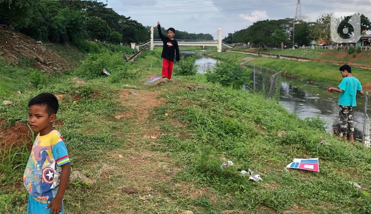 Anak-anak bermain di sekitar bantaran Kanal Banjir Timur (KBT), kawasan Cipinang Muara, Jakarta, Selasa (16/6/2020). Sebagian besar warga masih mengabaikan protokol kesehatan dengan tidak menjaga jarak serta tanpa menggunakan masker. (Liputan6.com/Immanuel Antonius)