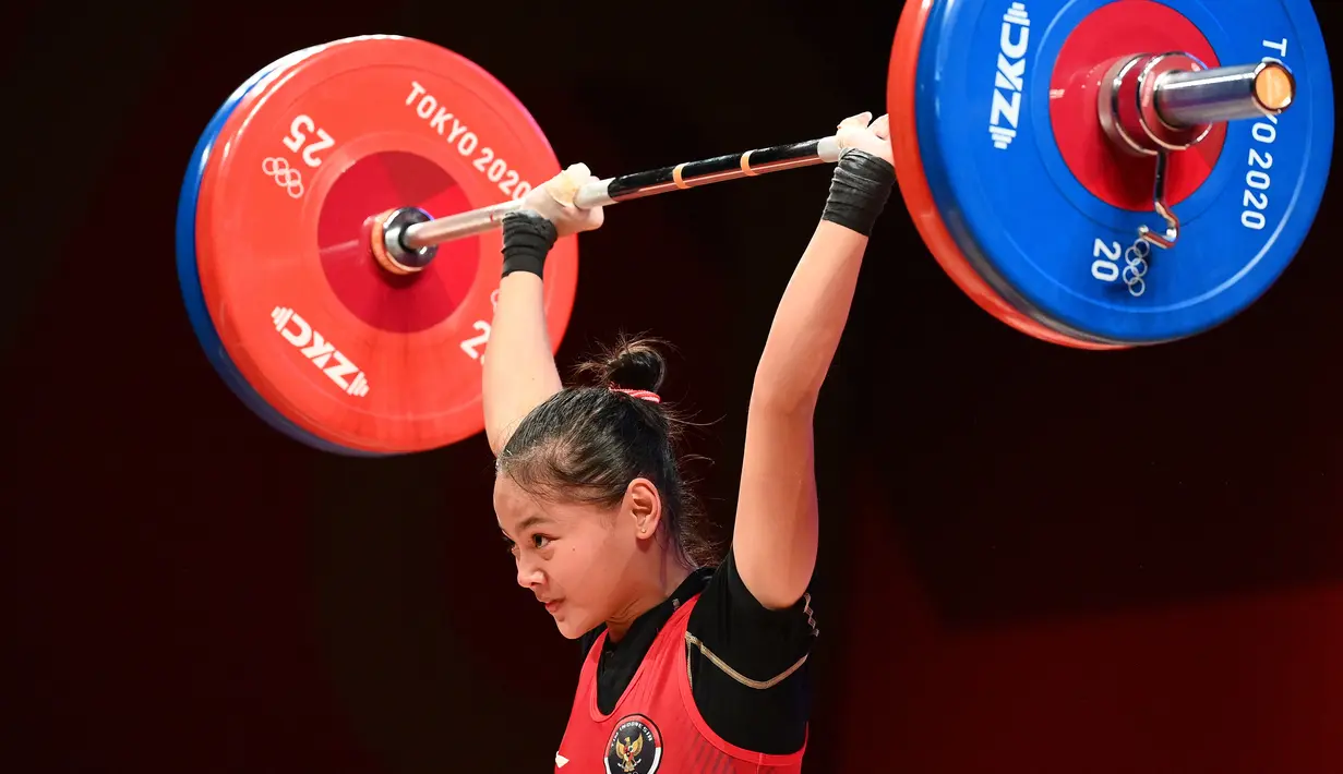 Lifter putri Indonesia Windy Cantika Aisah melakukan angkatan snatch dalam kelas 49 Kg Putri Grup A Olimpiade Tokyo 2020 di Tokyo International Forum, Sabtu (24/7/2021). Windy Cantika mempersembahkan medali pertama bagi Indonesia yakni perunggu dengan total angkatan 194 Kg. (Vincenzo PINTO/AFP)