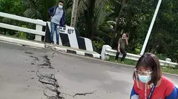 Relawan melihat retakan di jalan setelah gempa melanda Cataingan, Filipina tengah (18/8/2020). Badan seismologi Filipina menyatakan tidak ada potensi tsunami yang dipicu oleh gempa ini, namun warga diperingatkan akan adanya gempa susulan. (John Mark Lalaguna/Philippine National Red Cross via AP)