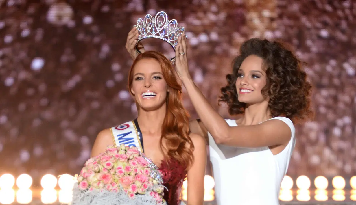 Miss Nord-Pas-de-Calais, Maeva Coucke (kiri) menerima mahkota dari Miss France 2017 Alicia Aylies setelah memenangkan kontes Miss France 2018 di Chateauroux, Prancis tengah (16/12). (AFP Photo/Guillaume Souvant)