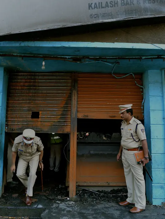 Polisi India mengecek restoran yang terbakar di Bangalore (8/1). Lima pekerja restoran tewas akibat kebakaran tersebut. Menurut Polisi, kurang dari dua minggu kebakaran telah terjadi di restoran lain menewaskan 14 orang. (AFP Photo/Manjunath Kiran)