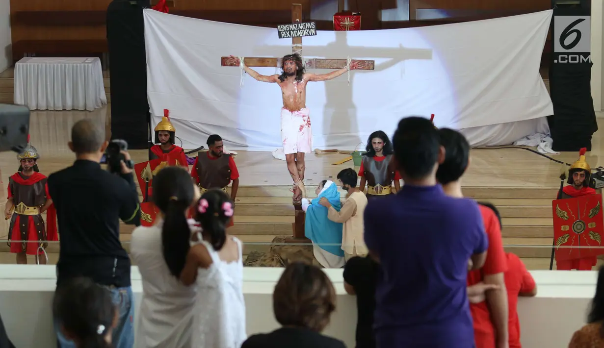 Jemaat mengambil gambar penyaliban Yesus dalam teatrikal prosesi jalan salib di Gereja Santa Maria Regina Bintaro, Tangerang Selatan, Banten, Jumat (30/3). Prosesi ini bagian dari perayaan Paskah yang dirayakan umat Kristian. (Liputan6.com/Angga Yuniar)