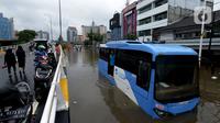 Bus transjakarta terendam banjir di Jalan Raya Daan Mogot, Jakarta, Rabu (1/1/2020). Hujan yang turun saat malam pergantian tahun baru 2019-2020 menyebabkan sejumlah titik jalan terputus di kawasan Grogol terendam banjir. (merdeka.com/Imam Buhori)