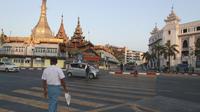 Orang-orang menyeberang jalan dekat Pagoda Sule di Yangon, Myanmar pada Senin (1/2/2021). Militer Myanmar resmi merebut kekuasaan pemerintah usai menahan Kanselir Aung San Suu Kyi dan Presiden Myint pada Senin pagi (1/2). (AP Photo/Thein Zaw)