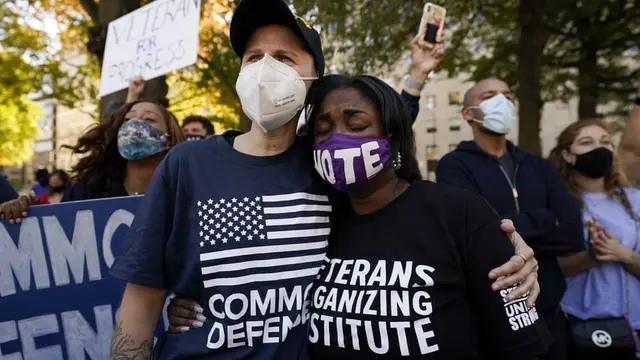 Orang-orang yang berkumpul di Black Lives Matter Plaza untuk mendukung Joe Biden (AP)