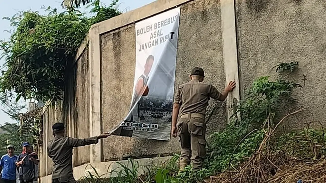 Anggota Satpol PP Kota Depok saat menurunkan spanduk Sekda Kota Depok, Supian Suri saat kegiatan ngubek Empang di Cilodong, Depok.