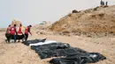 Petugas Bulan Sabit Merah Libya mengumpulkan jenazah para imigran yang ditemukan terdampar di pantai utara Libya, Selasa (21/2). Setidaknya terdapat 74 jenazah yang terdampar di pantai yang terhubung dengan Laut Mediterania tersebut. (MOHANED KREMA/AFP)