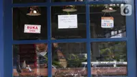 Seorang pria berada di balik kaca sebuah kedai kopi yang tutup di kawasan Sabang, Jakarta, Sabtu (3/7/2021). Rumah makan hingga restoran diizinkan buka hanya untuk melayani layanan delivery order atau takeaway selama PPKM Darurat. (Liputan6.com/Angga Yuniar)