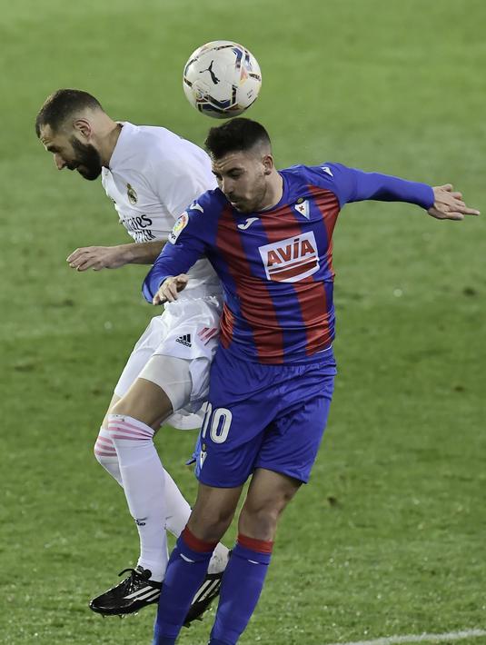 Penyerang Real Madrid, Karim Benzema dan gelandang Eibar, Edu Exposito berebut bola pada laga lanjutan Liga Spanyol di Stadion Ipurua, Senin dinihari WIB (21/12/2020). Benzema menjadi pahlawan dalam kemenangan Madrid karena menciptakan satu gol dan dua assist di laga tersebut. (AP/Alvaro Barrientos)