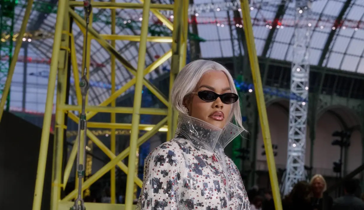 Sementara itu, Teyana Taylor menghadirkan gaya paling eksperimental malam itu. Ia mengenakan mantel transparan dengan kerah tinggi yang dilapiskan di atas dress bermotif, menciptakan efek futuristik sekaligus avant-garde.