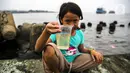 Seorang anak menunjukkan air dari Kali Adem, Muara Angke, Jakarta Utara, Sabtu (2/10/2021). Teluk Angke dan Ancol yang ada di wilayah Jakarta Utara dilaporkan tercemar paracetamol dengan konsentrasi tinggi. (Liputan6.com/Faizal Fanani)