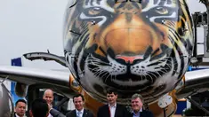 Pengunjung berpose di depan pesawat Embraer E190-E2 yang dipamerkan pada ajang Singapore Airshow 2018 di Changi, Singapura, (7/2). Embraer memamerkan secara perdana pesawat E190-E2 dengan design harimau dibagian kepala. (AP Photo / Yong Teck Lim)
