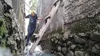 Ngadenin (63), warga Jalan Raya Jatiwaringin RT 03 RW 04 Jati Cempaka, Pondok Gede, Kota Bekasi, terpaksa harus melewati saluran got untuk menuju rumahnya, karena akses jalan tertutup tembok hotel. (Istimewa)