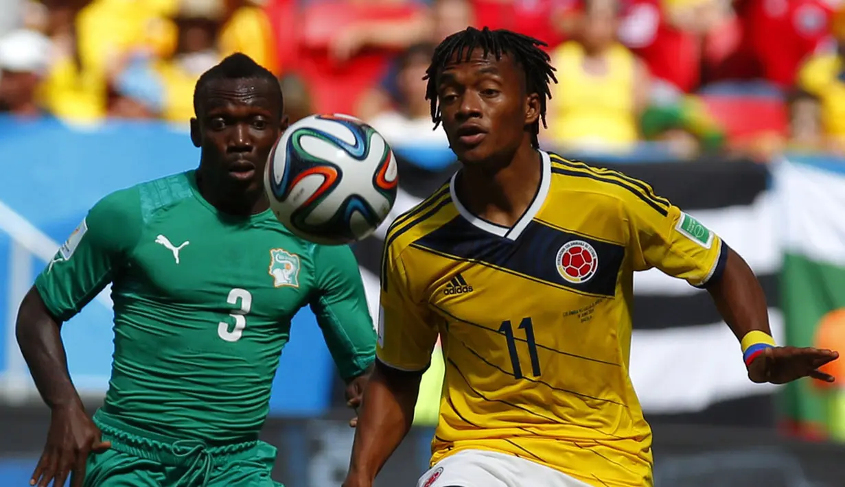 Pemain belakang Pantai Gading, Arthur Boka (kiri) berusaha merebut bola dari gelandang Kolombia, Juan Cuadrado, saat berlaga di penyisihan Piala Dunia 2014 Grup C di Stadion National Mane Garrincha, Brasil, (19/6/2014). (REUTERS/Paul Hanna) 