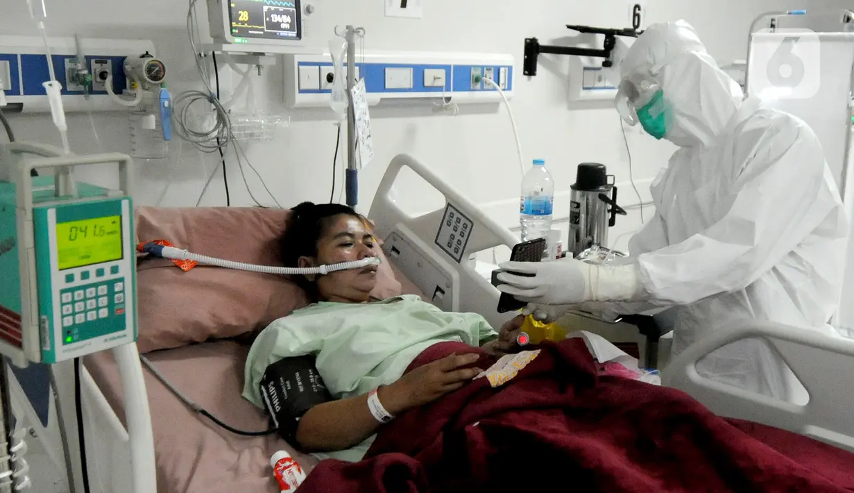 Paramedis menunjukkan gawai kepada pasien COVID-19 di Ruang ICU RSUD Kota Bogor, Jawa Barat, Jumat (18/6/2021). Tingkat keterisian tempat tidur atau Bed Occupancy Rate (BOR) RSUD Kota Bogor saat ini mencapai 73 persen. (merdeka.com/Arie Basuki)